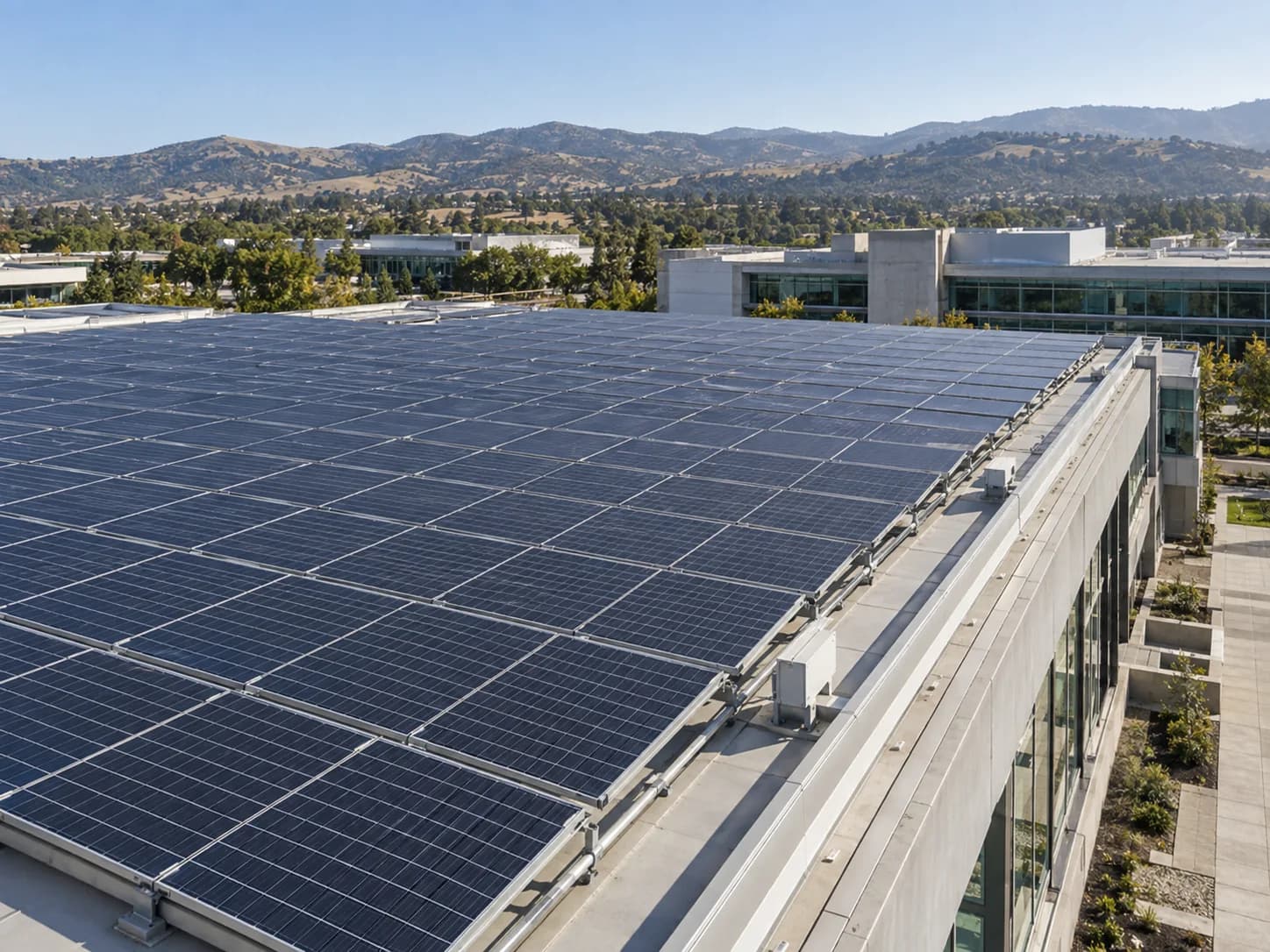 Elevated view across a photovoltaic rooftop, service walkway and engineering campus facade in daylight